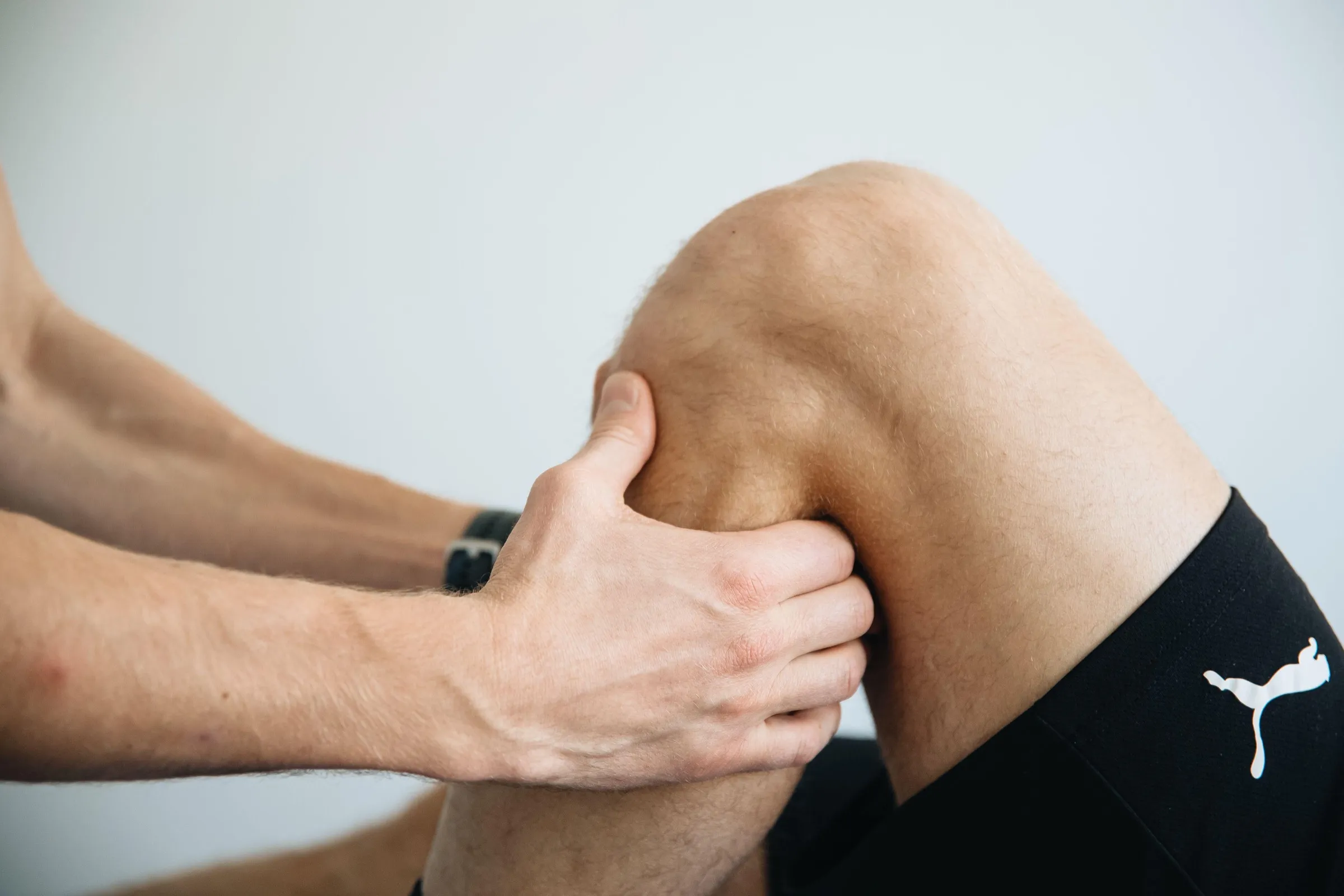 Untersuchung beim Check-up: Zwei Hände tasten ein gebeugtes Knie ab