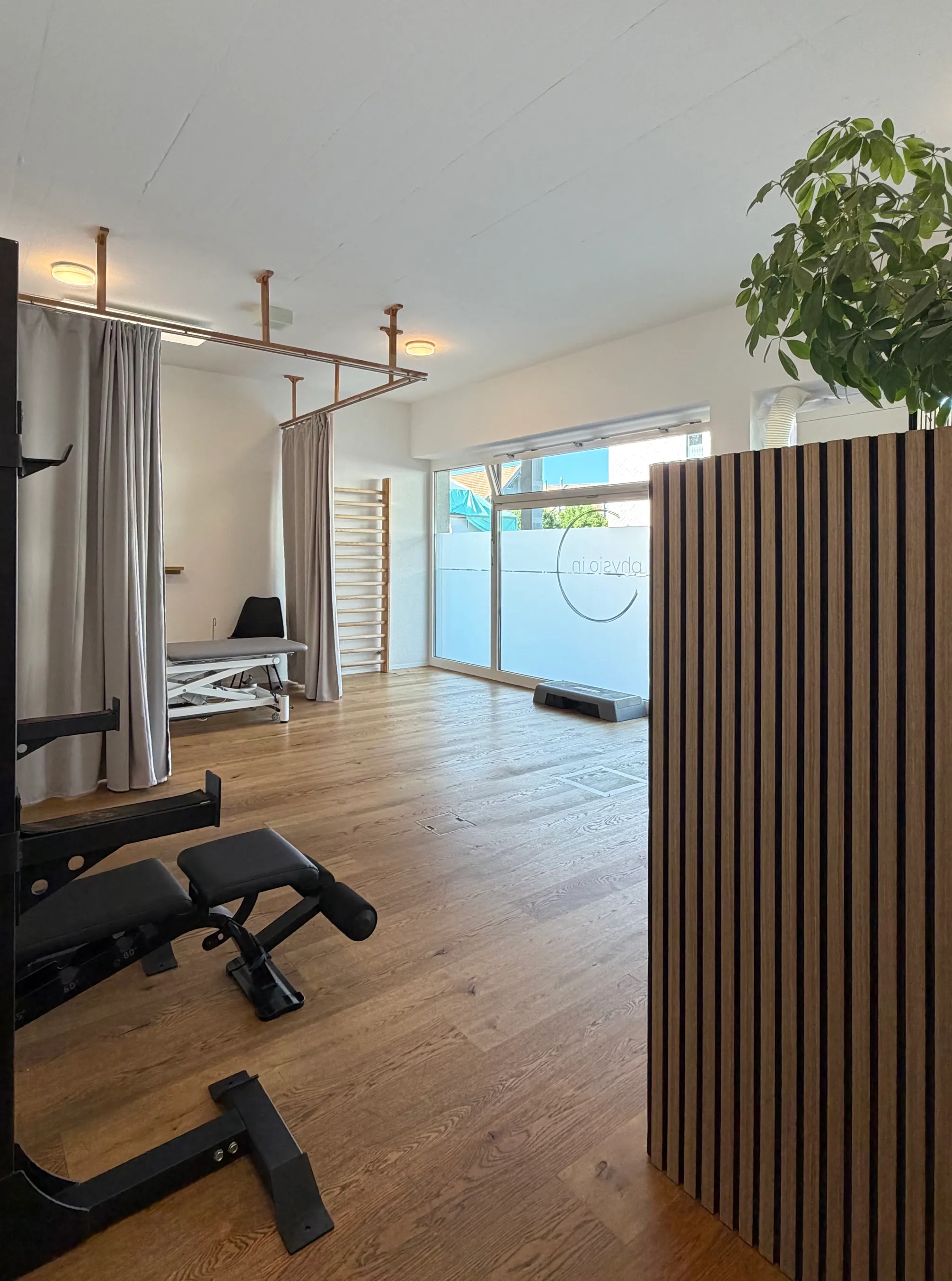 Praxisräumlichkeiten von physio in: Aktivraum mit Trainingsgeräten, Liege und grosser Fensterfront