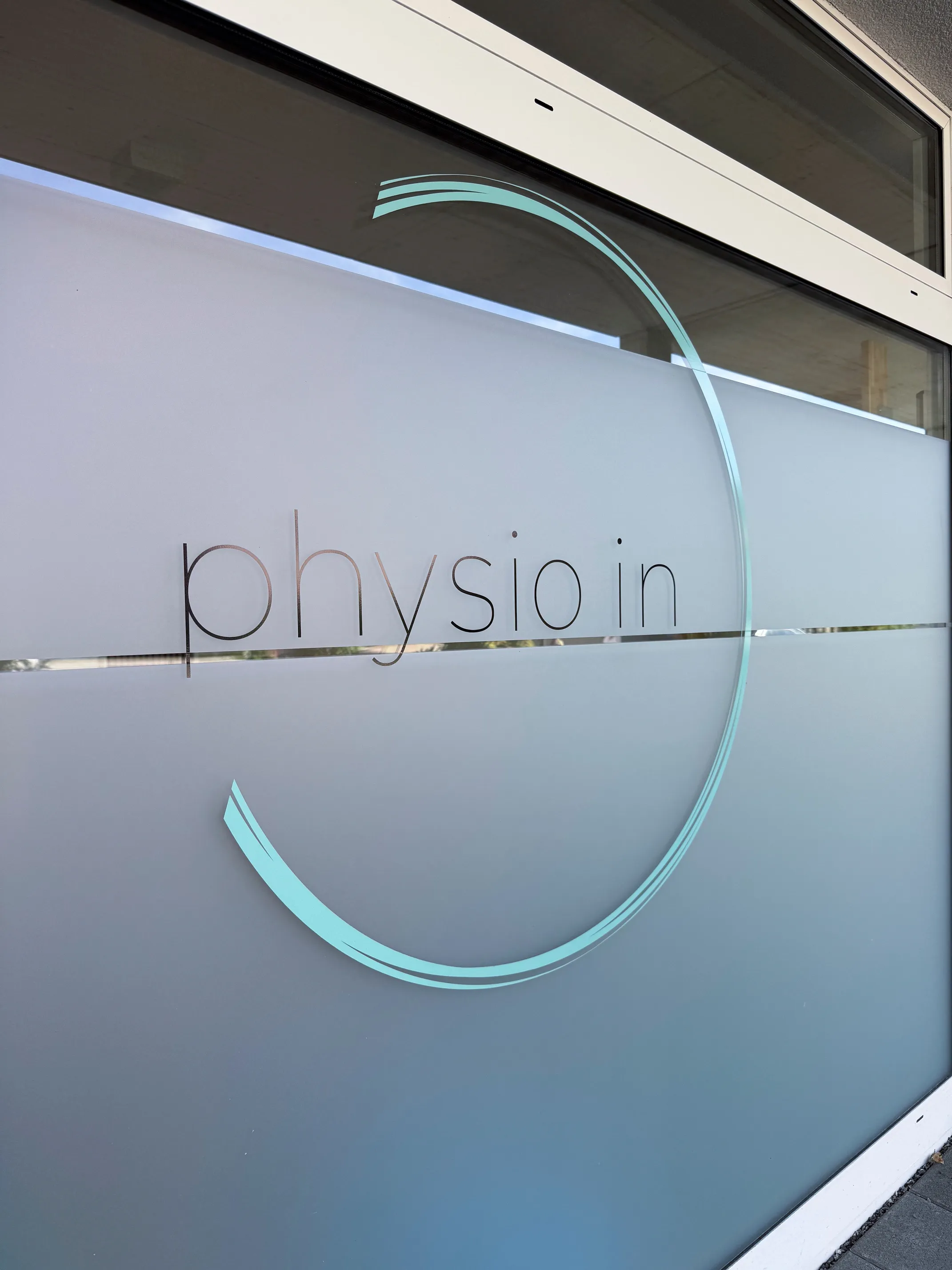 Praxisräumlichkeiten von physio in: Schriftzug und Logo von physio in auf der Fensterscheibe der Praxis